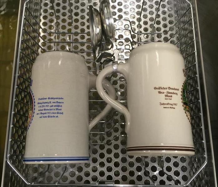 two mugs and silverware in a content cleaning basket