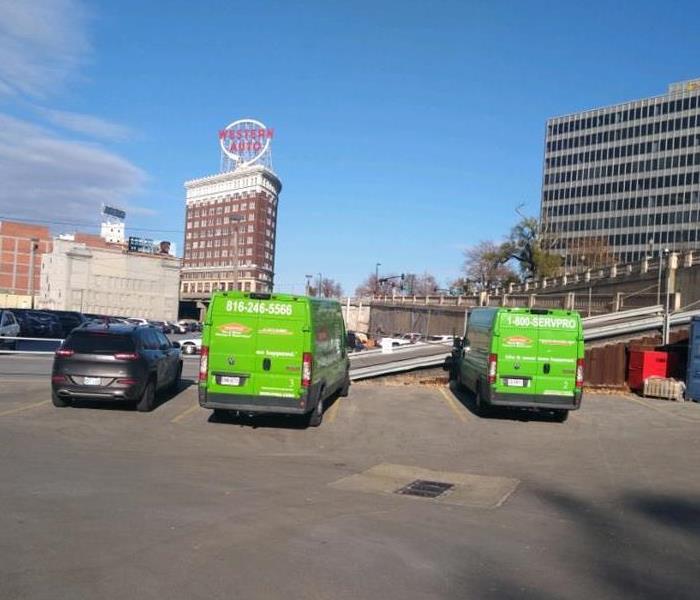 two green vans in the parking lot of a city